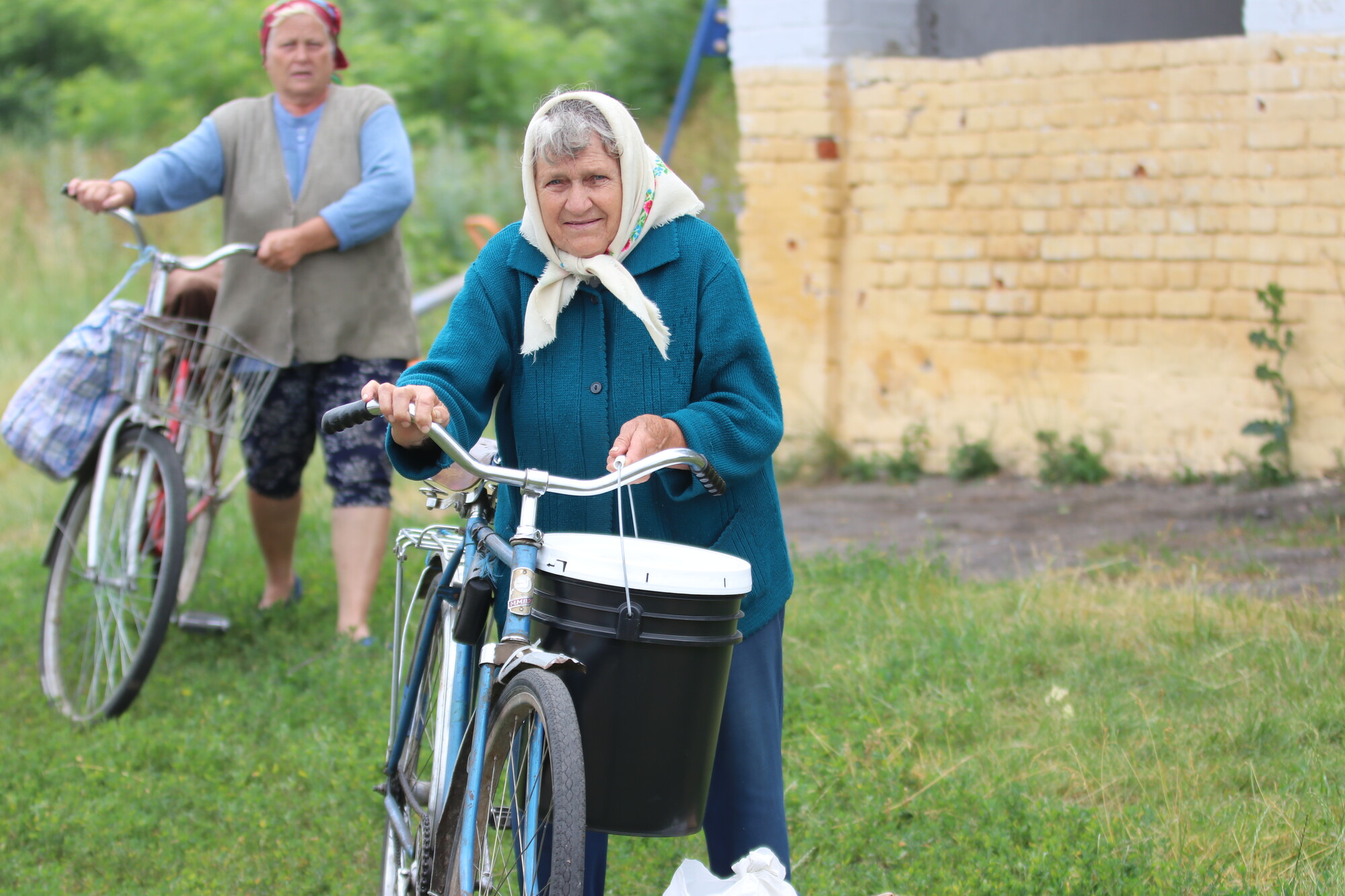 A woman holding a bike and relief bucket