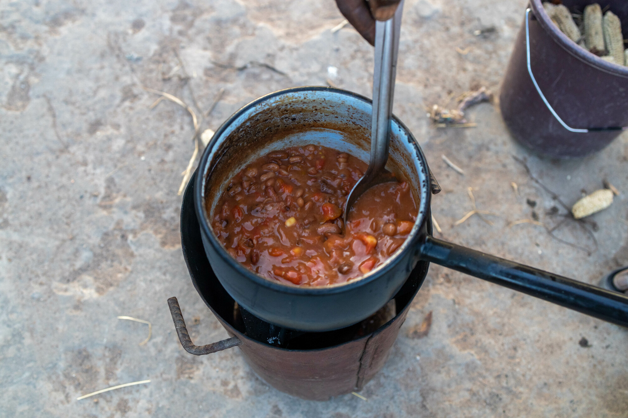 A pot of beans cooking over a small outdoor stove