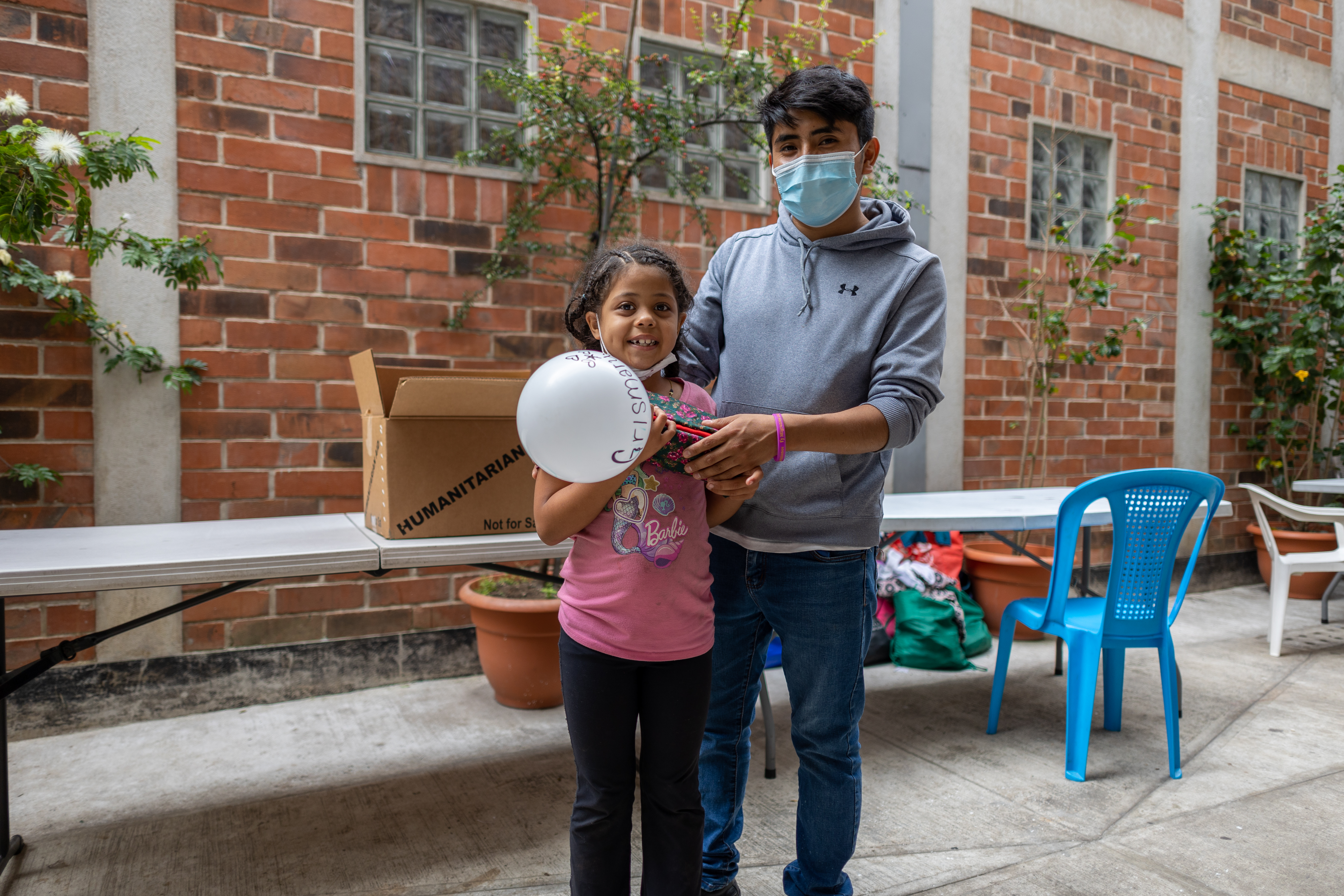 Hector Pablo, staff, hands out a hygeine kit to Crismary Olarfe at Casa del Migrante in Guatemala City.