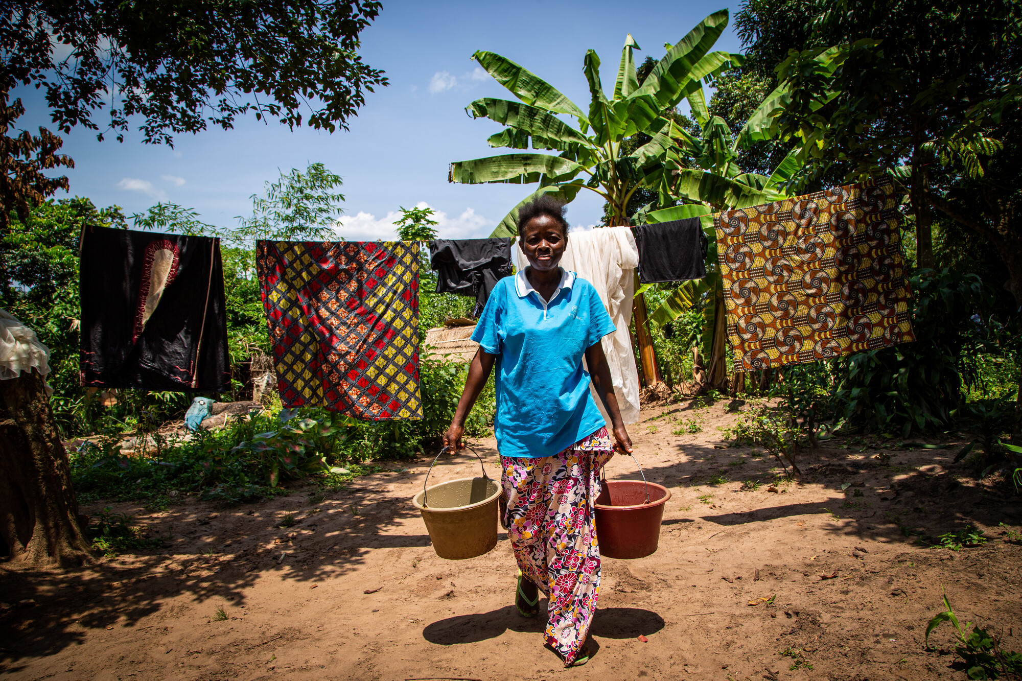 A young woman carrying two buckets of water