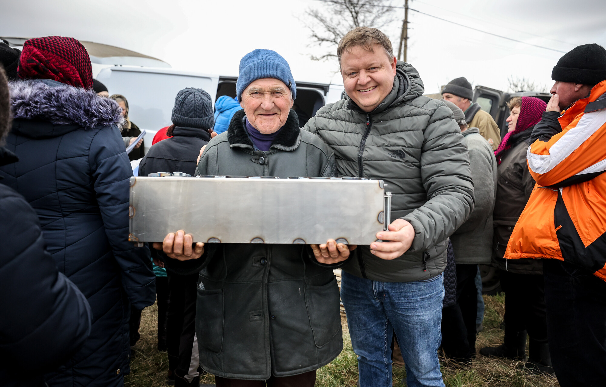 Two men holding a large metal box.