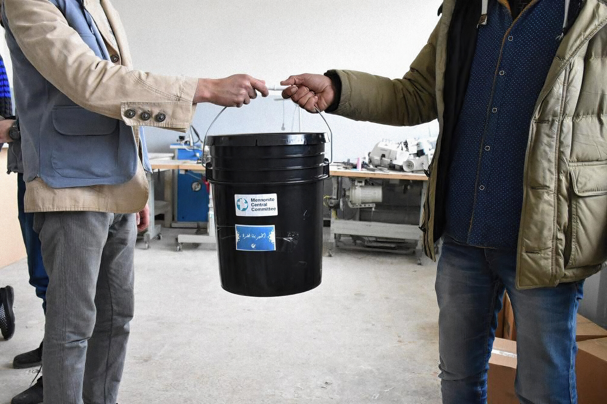 A person hands another person a 5 gallon bucket.