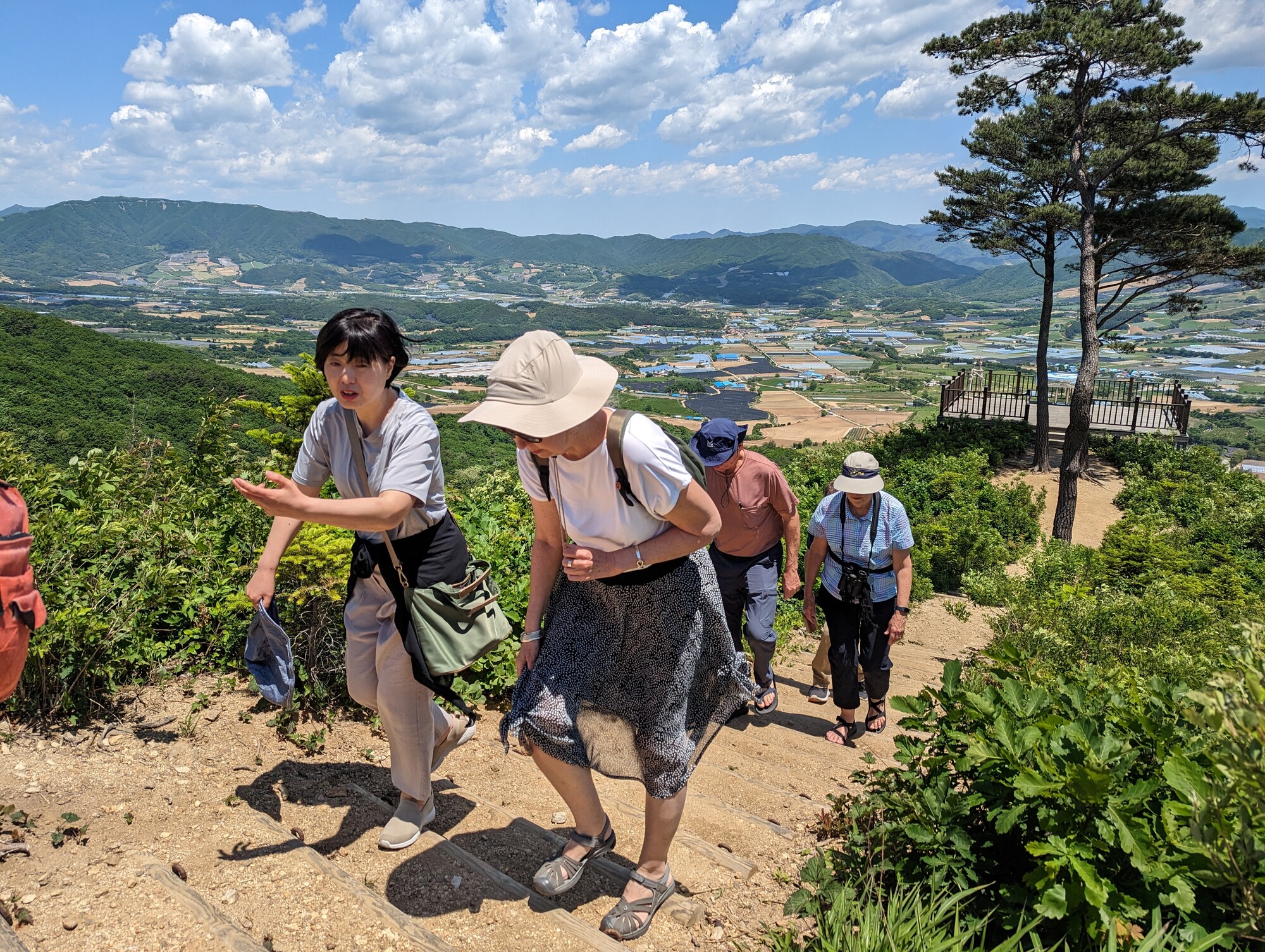 A group of people walking up a hill with a hilly landscape in the background