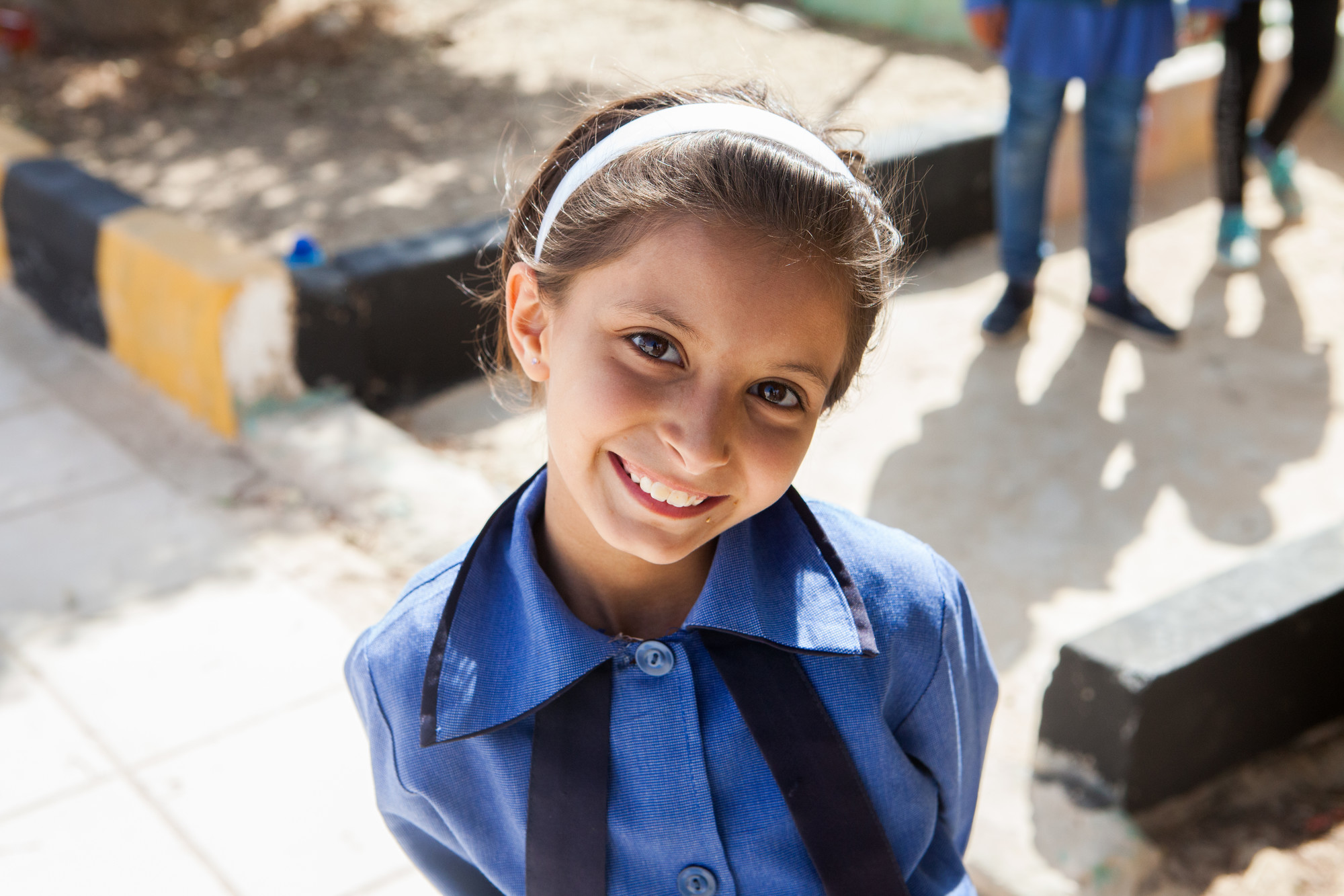 A girl in a blue school uniform smiles at the camera