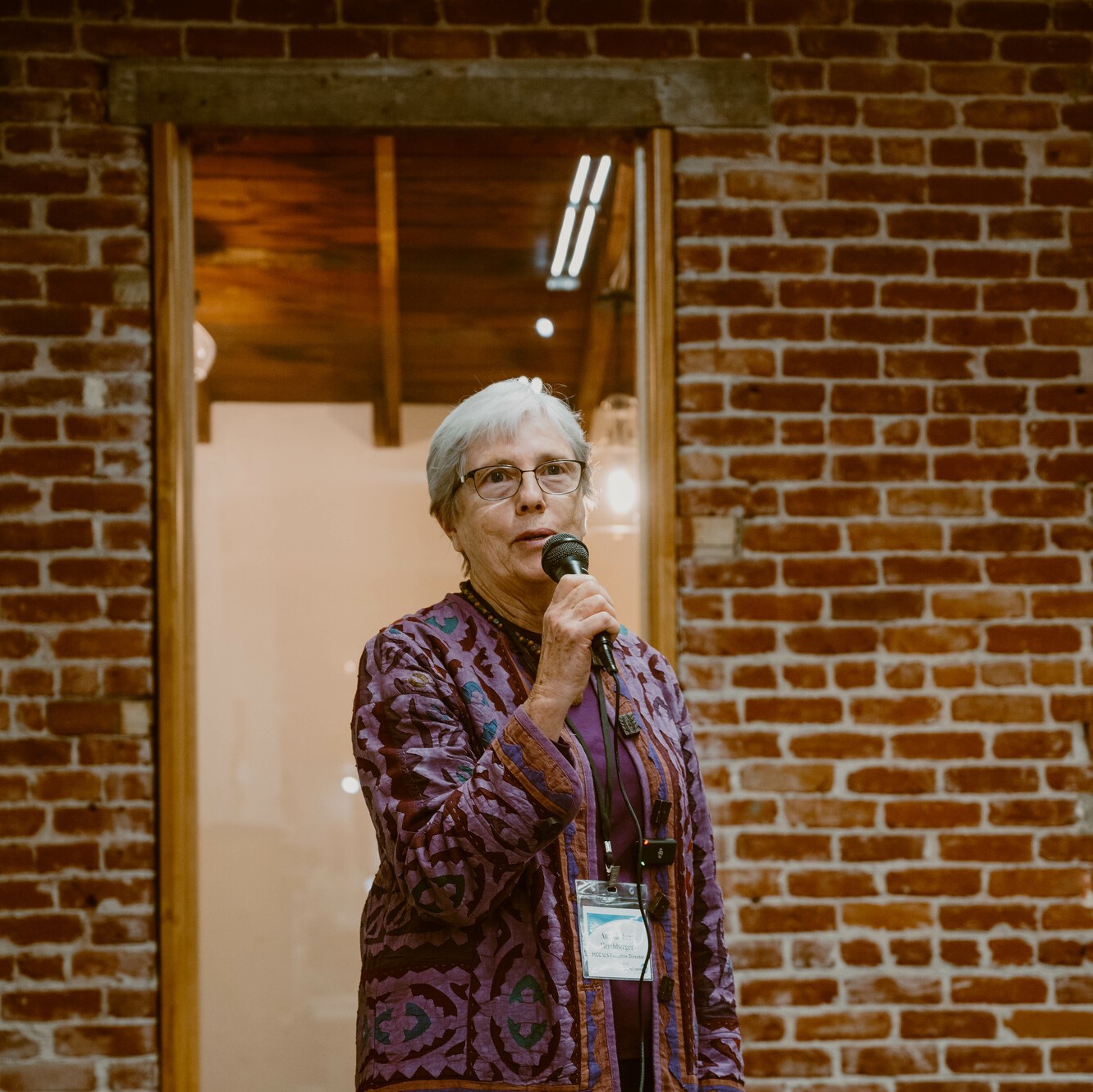 A photo of Ann Graber Hershberger speaking into a mic