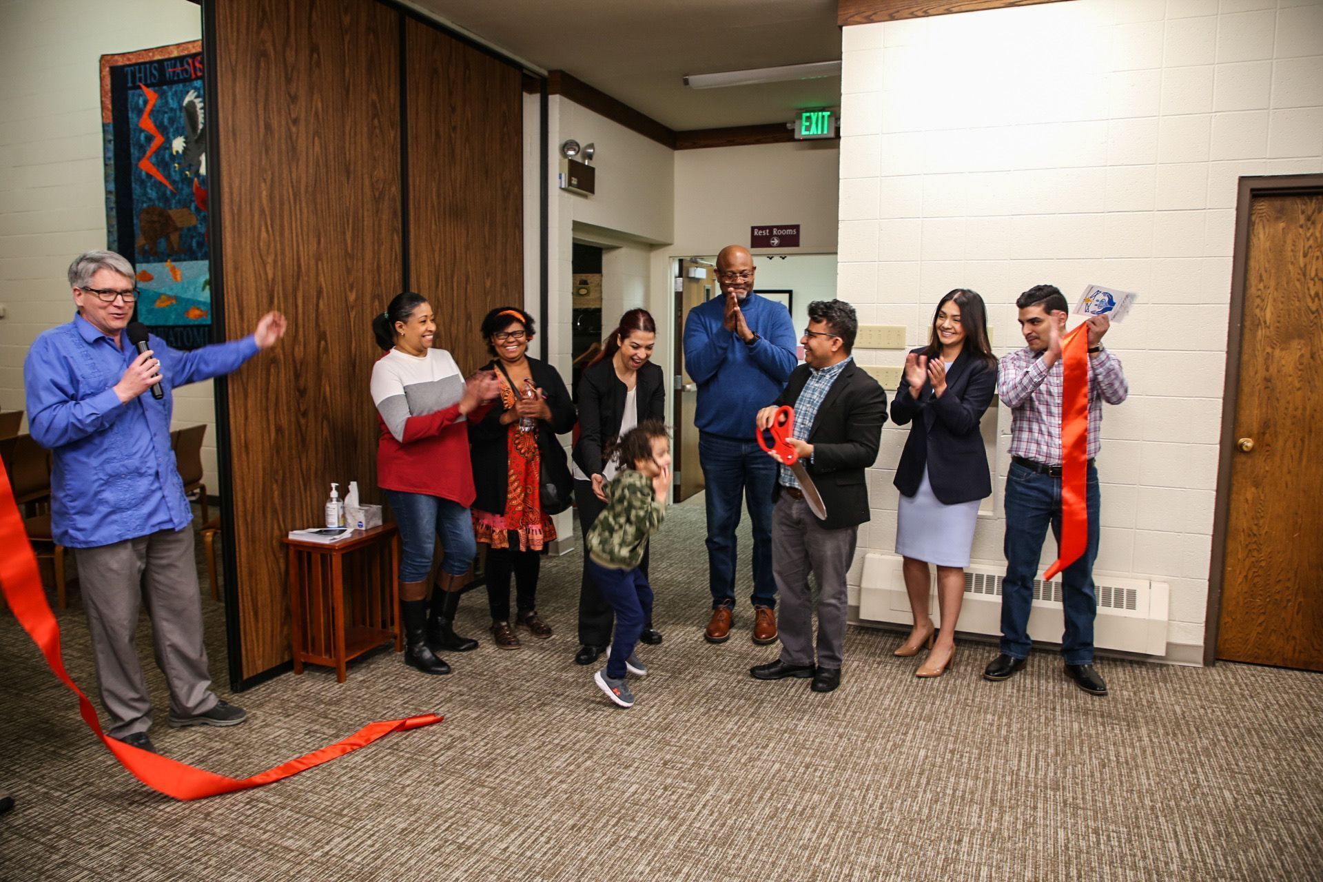 a group of men, women and one child standing and clapping