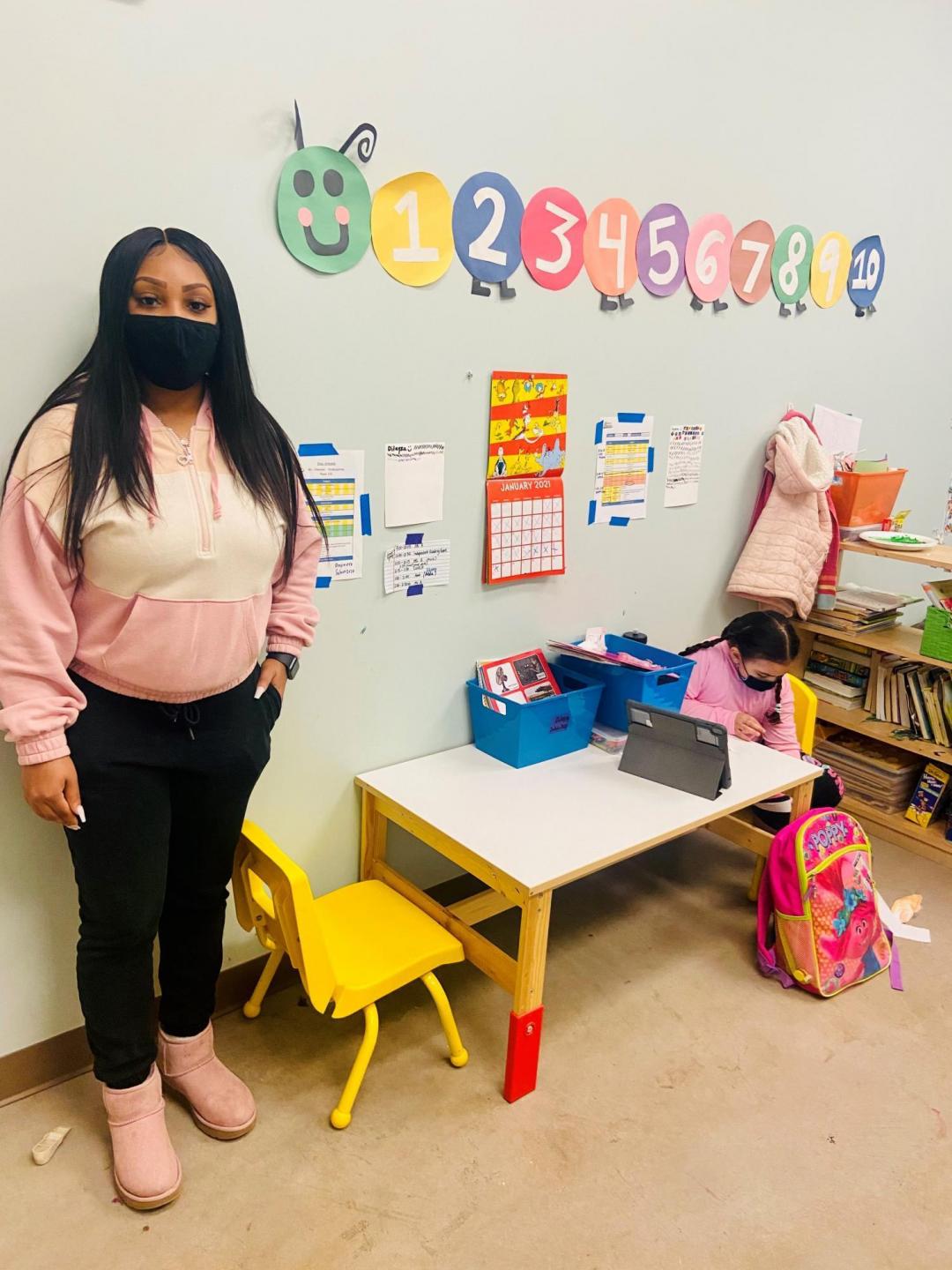 A young adult stands in a children's classroom