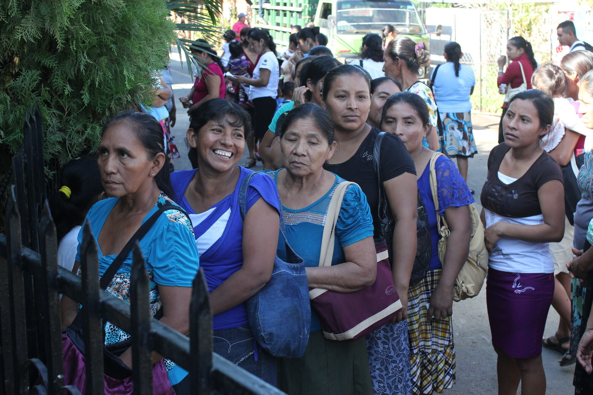 A group of Salvadoran woman waiting in line behind a fence