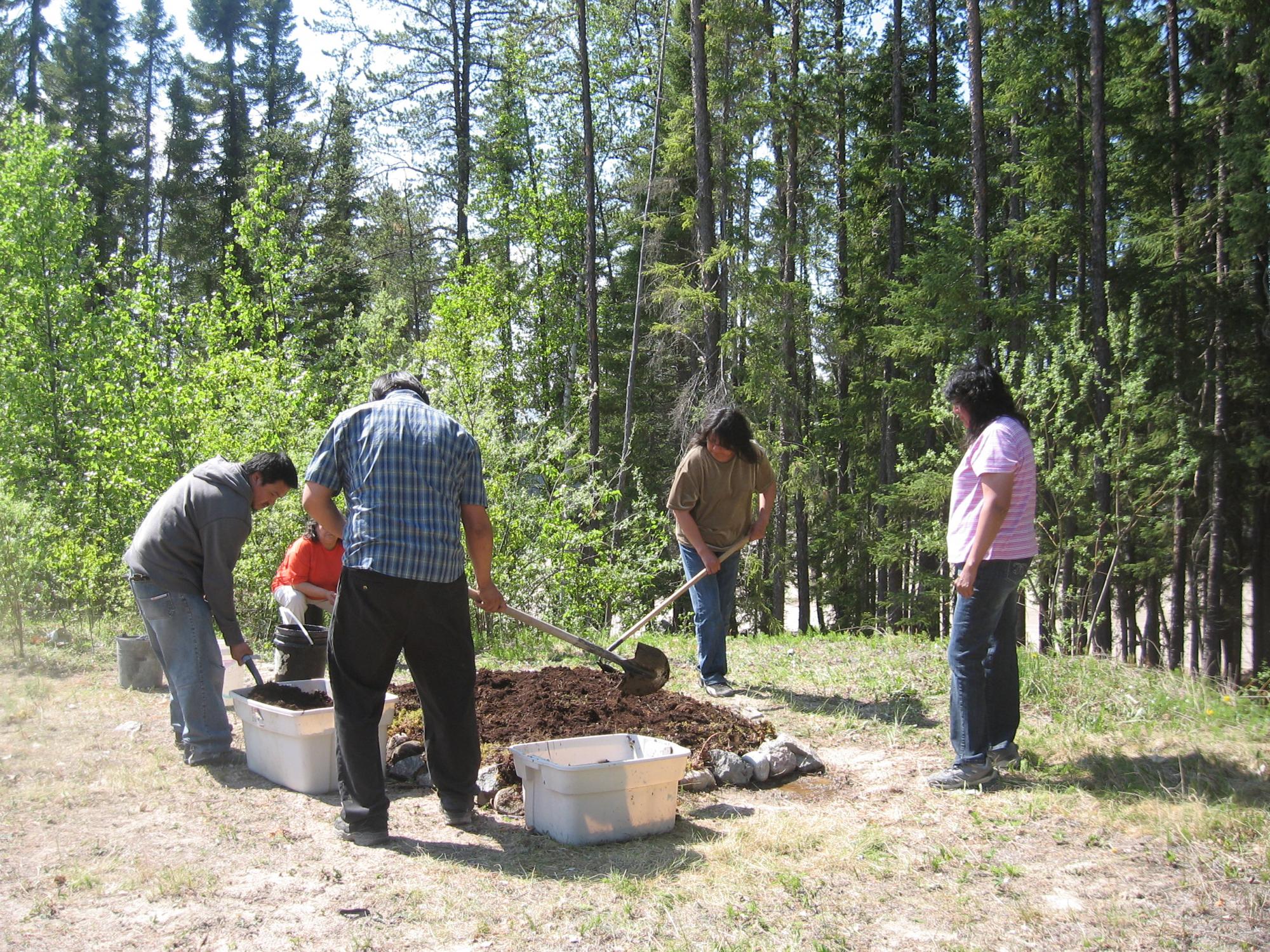 Five people work on digging a garden