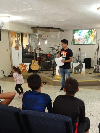 A man stands at a microphone in a front of a church congregation 