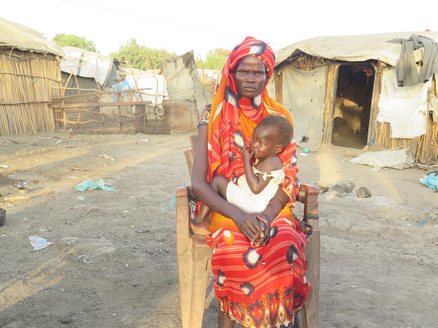 Nyarwot Bim Chan and one of her children, Gatkuoth, in front of their home in the Rubkona camp for internally displaced South Sudanese.