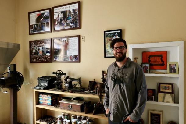 A man standing near a wall of historical artifacts 