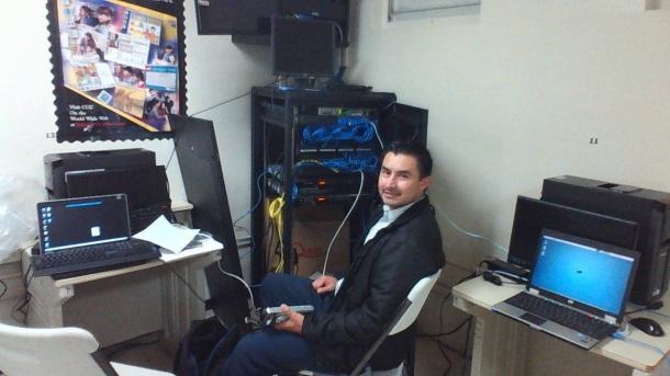 A man sits in front of computers and machines with blue wires