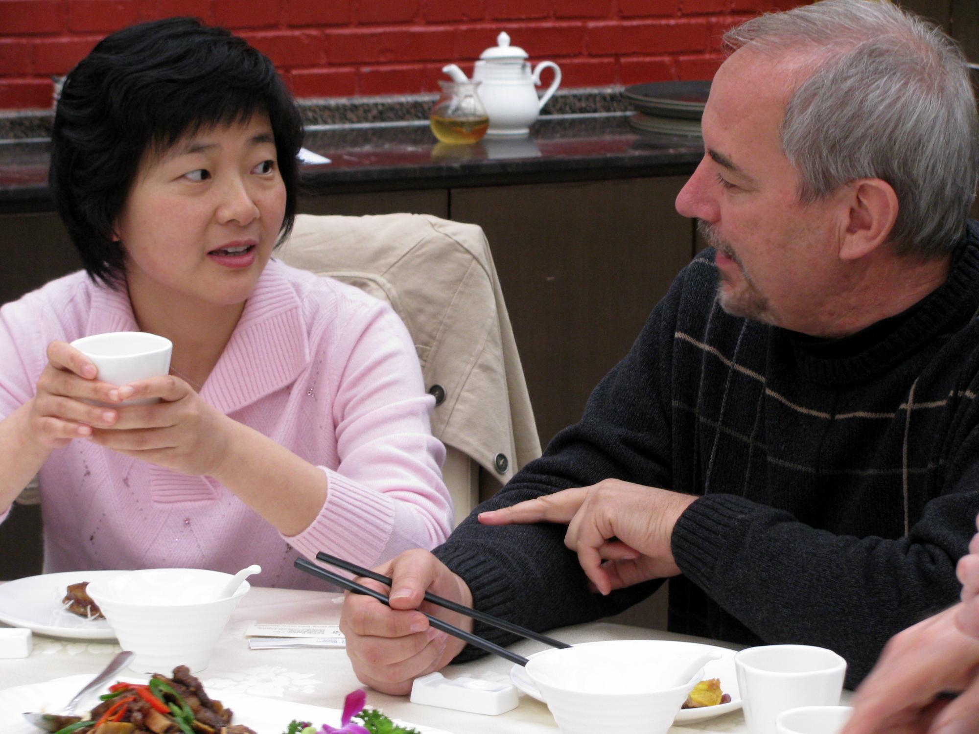Myrrl Byler (right) converses with a government official (name withheld for security reasons) over a shared meal in Beijing, China in 2015.
