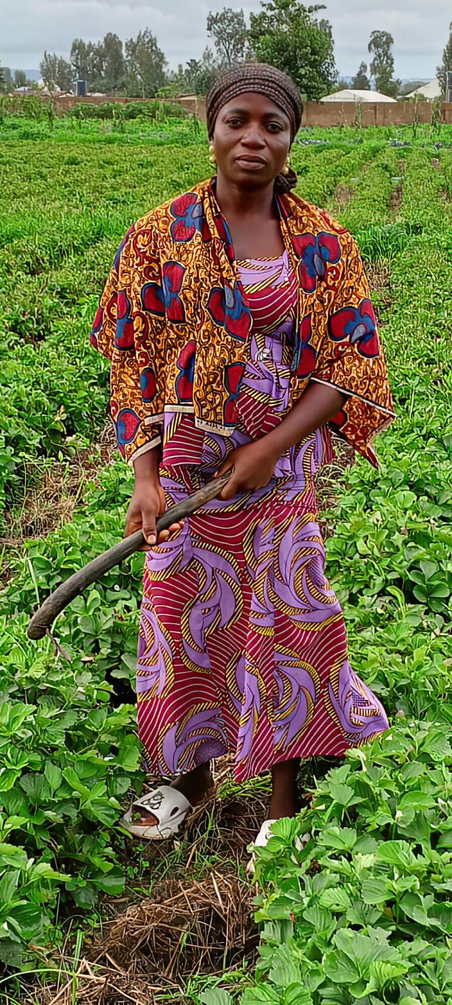A woman standing in a field holding a garden tool