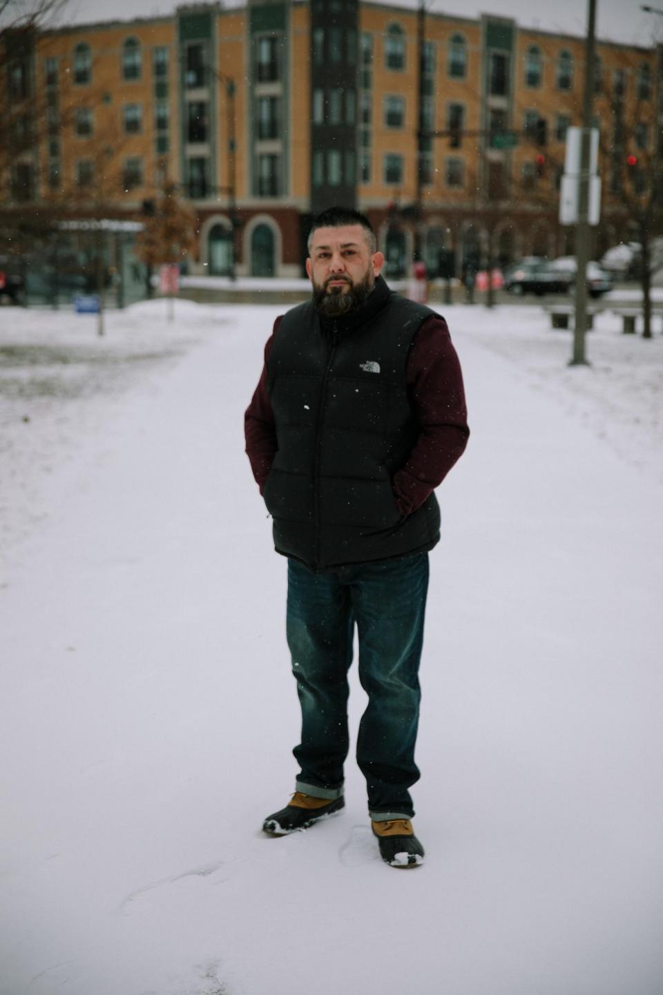 A man stands with his hands in his pockets in the snow.