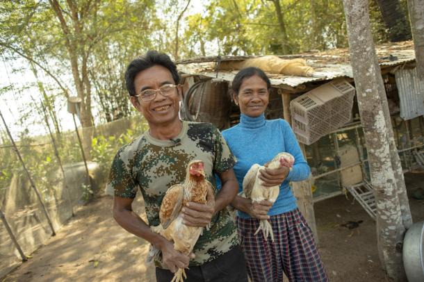 A Cambodian man and woman each hold a chicken.