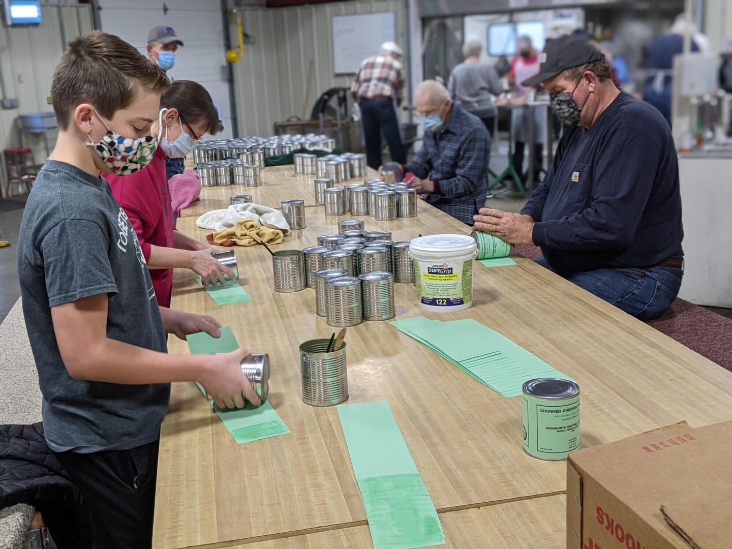 Gustav Huber (12), Alice Jantzen, Don Kauffman and Alan Entz put labels on meat cans at the MCC Material Resources Center in North Newton, Kansas.