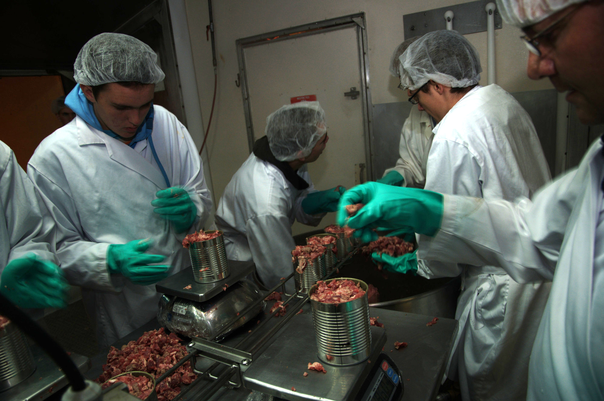 Volunteers weigh and adjust weight of meat cans