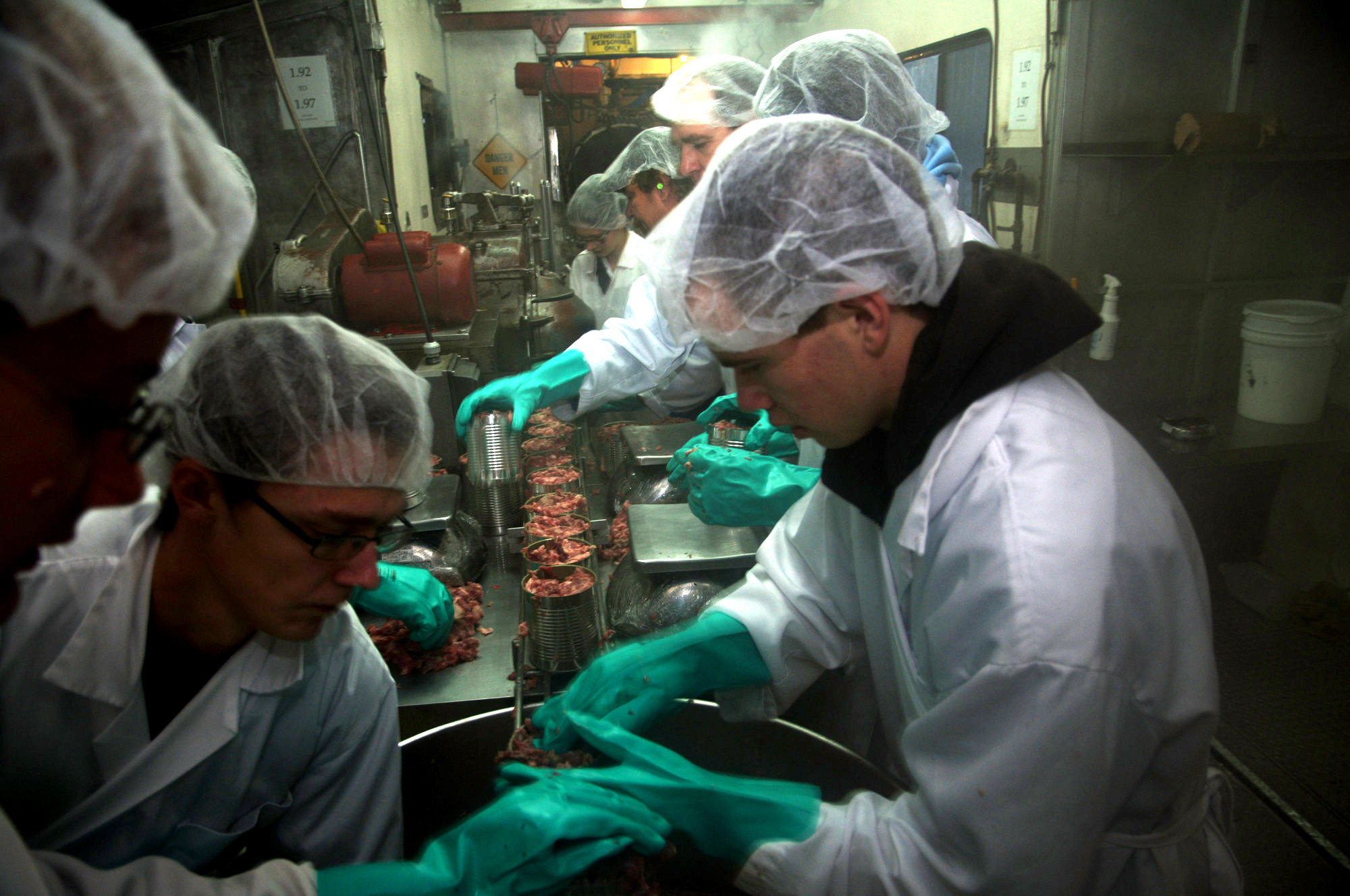 Volunteers put meat into cans