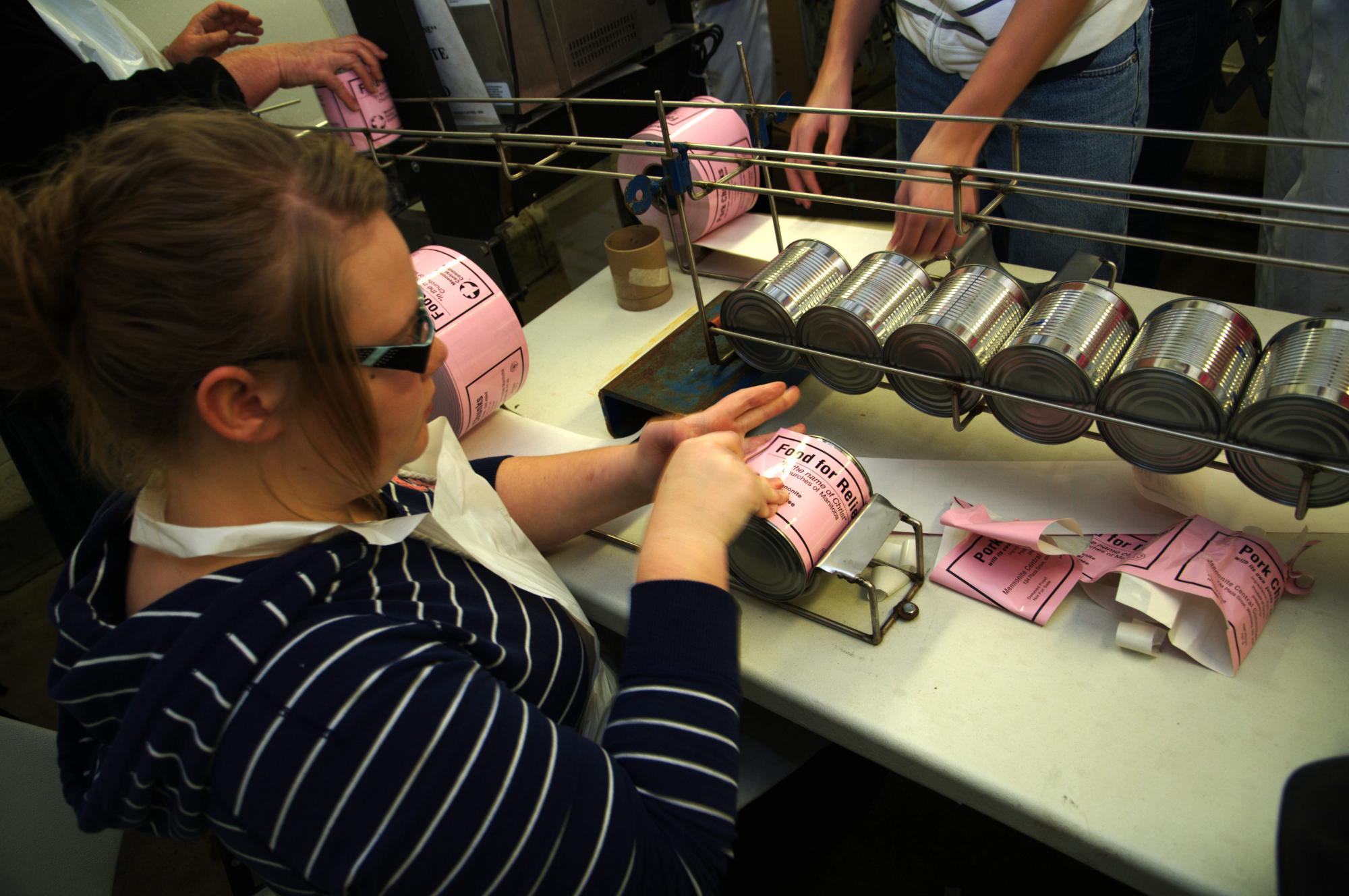 A volunteer applies a label to a can