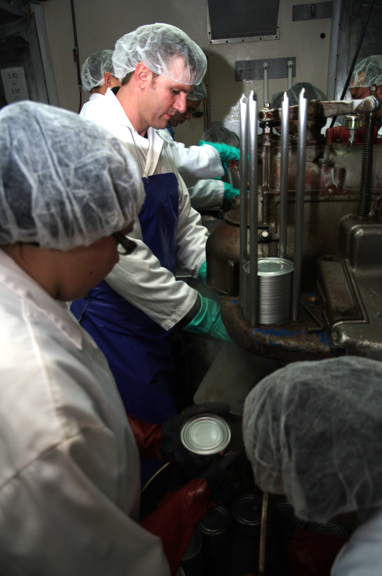 Canner puts cans through sealing machine