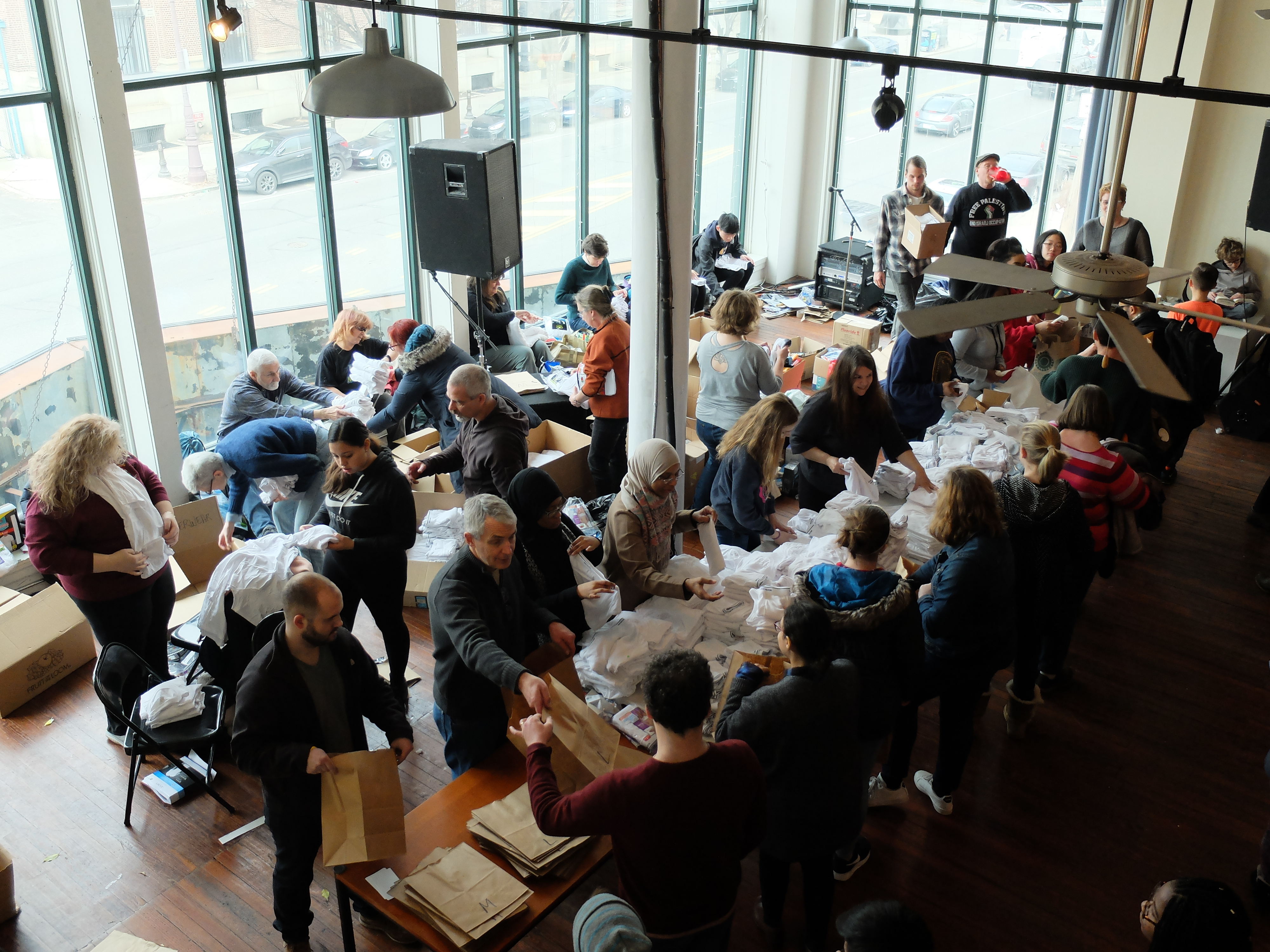 An overview perspective of a large group of people working on a makeshift assembly line on two long tables.