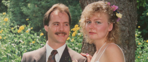 A photo of a man and woman. The man is looking at the woman while the woman looks directly at the camera.