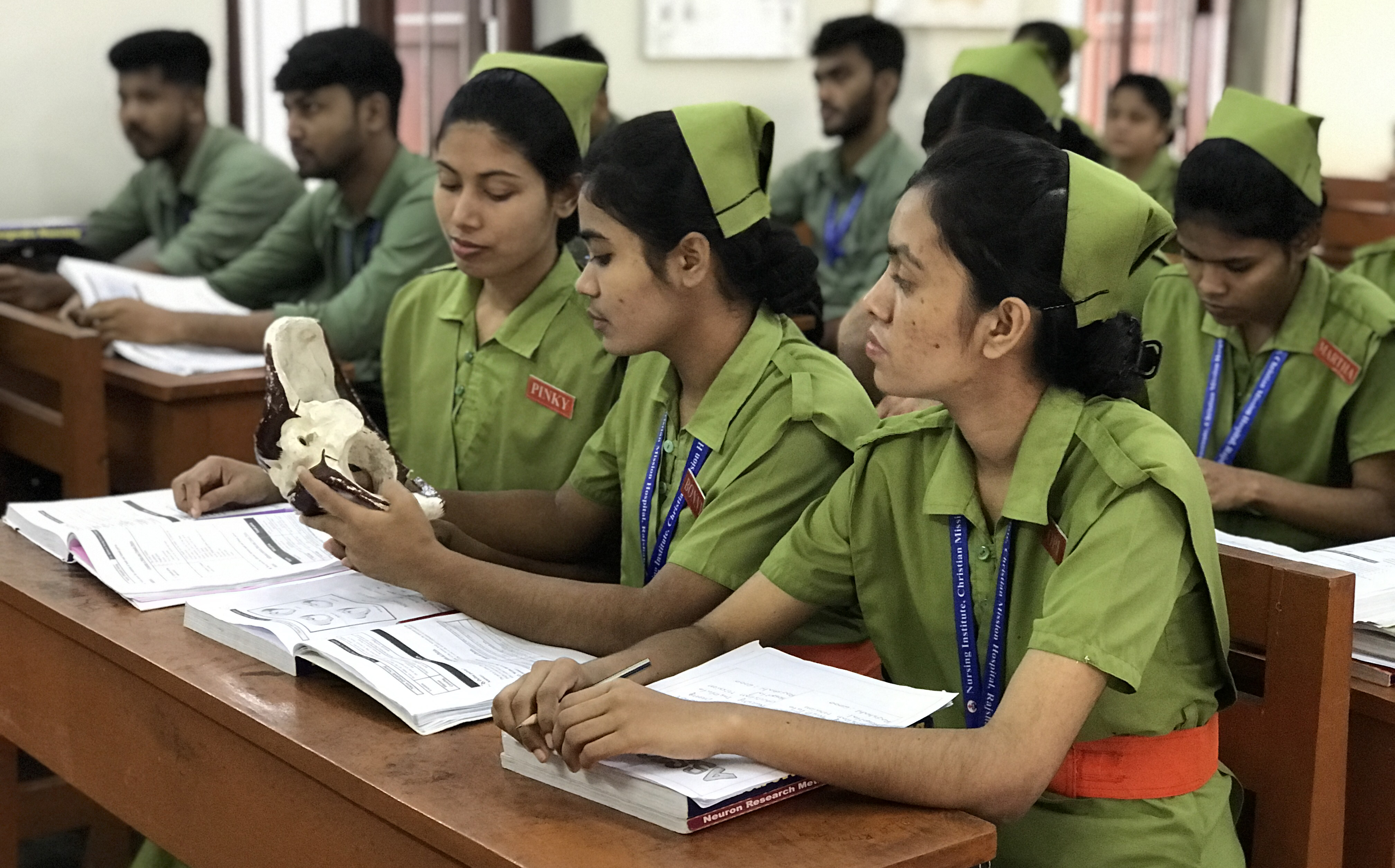 Nursing students sit at tables in a school classroom