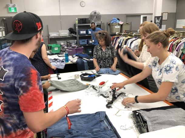 A group of people help sort clothes at a used clothing store