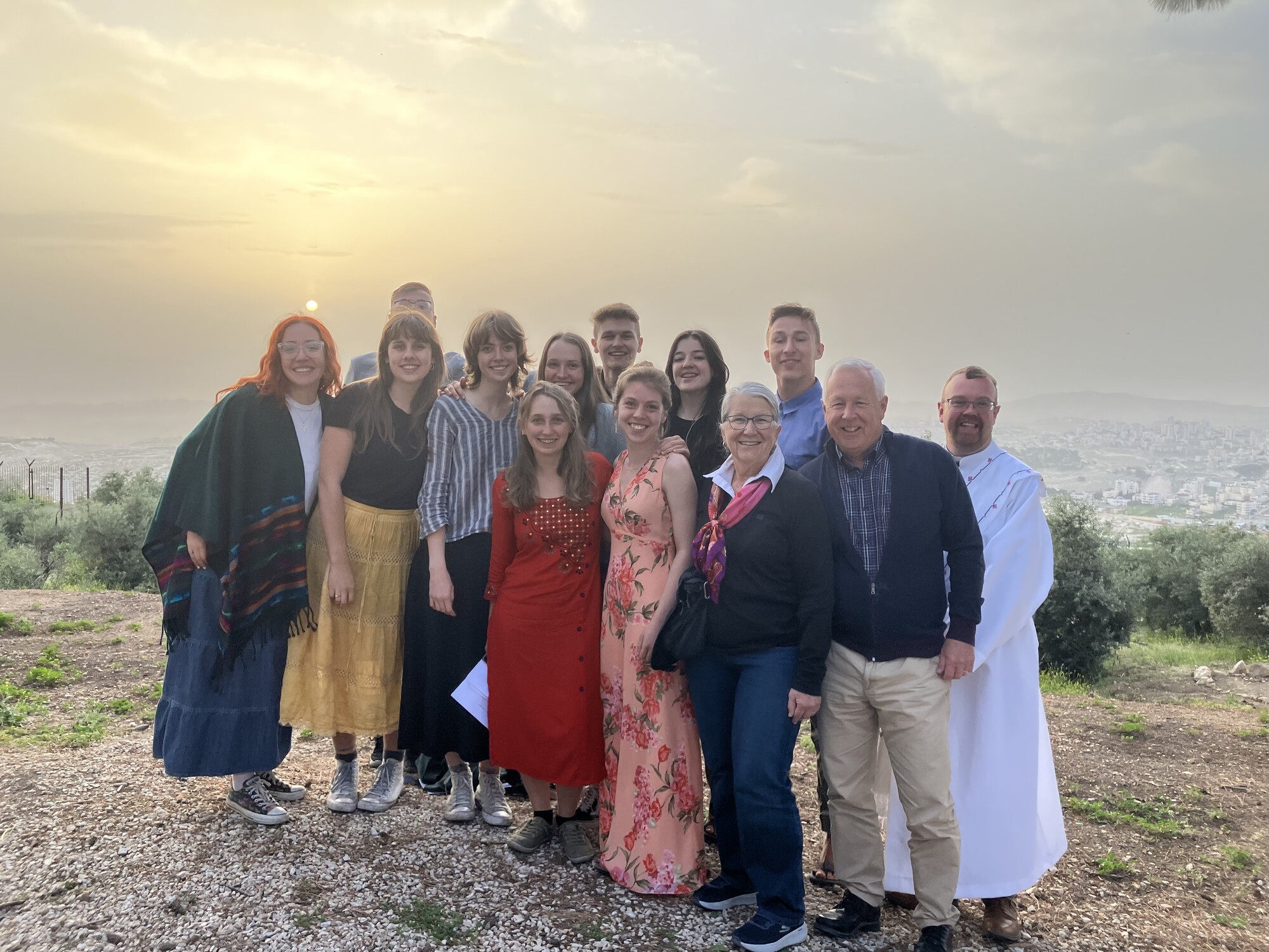 A group of people stand on a hilltop at sunrise