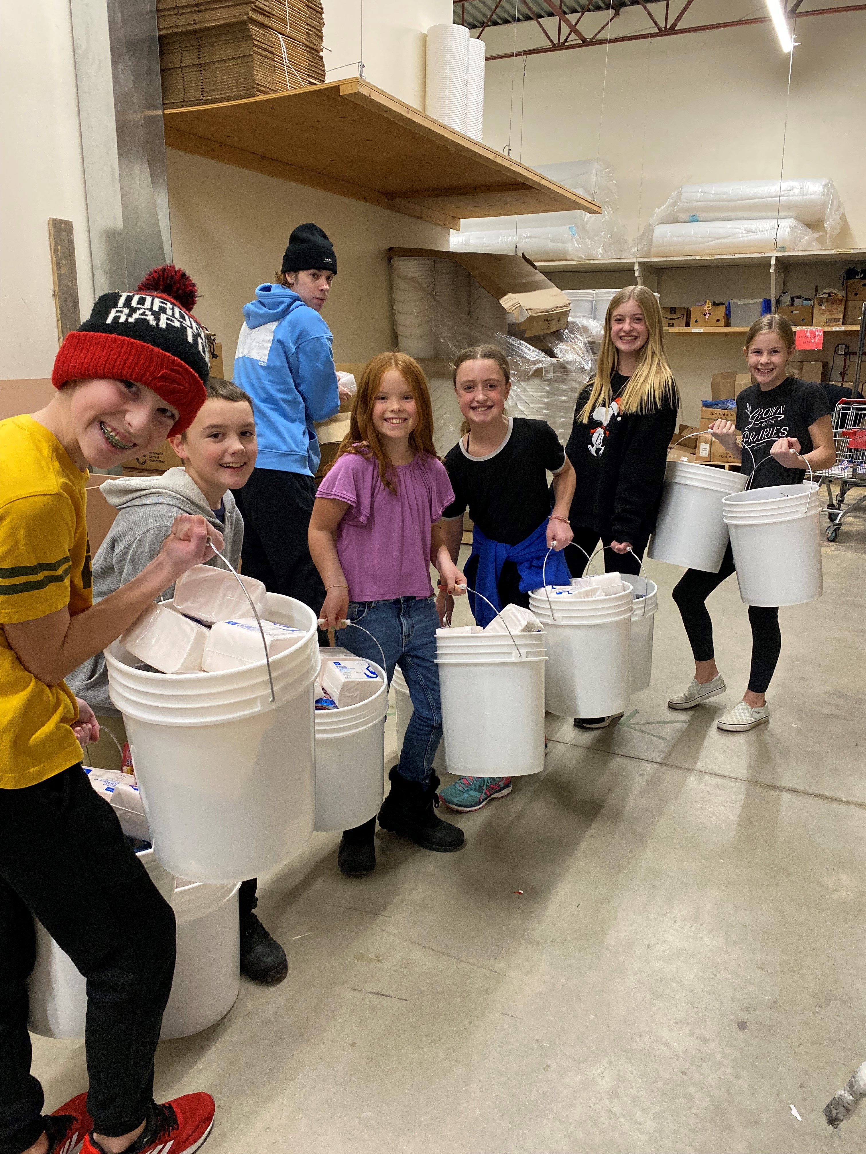 A group of kids stand with five-gallon buckets
