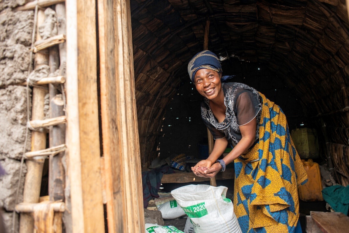 A woman in the DR Congo leans over a bag of dried beans in her hut