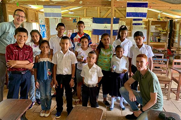 Two adults pose with a group of school children in Nicaragua