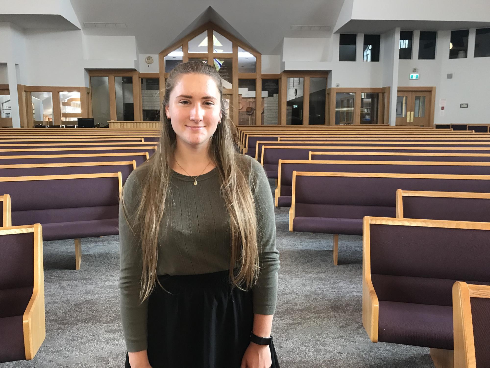 A young woman stands in a church sanctuary