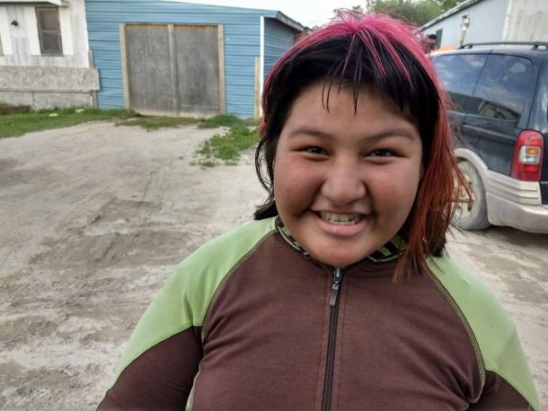A young Indigenous girl smiles for the camera.