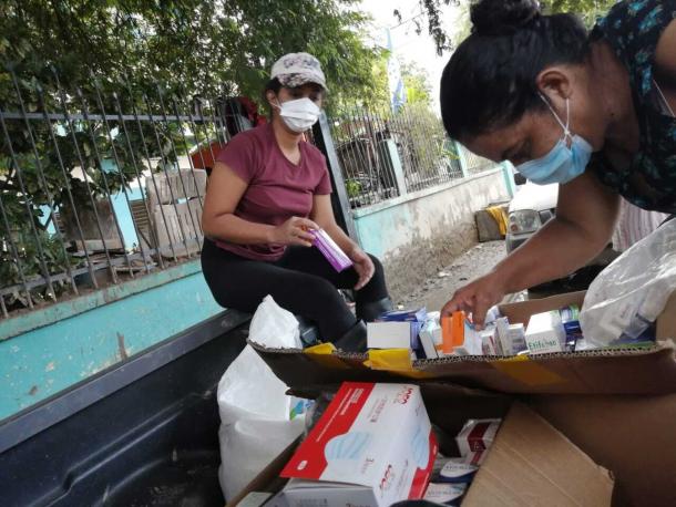 A young doctor and her mother sort through medication in boxes in the back of a truck