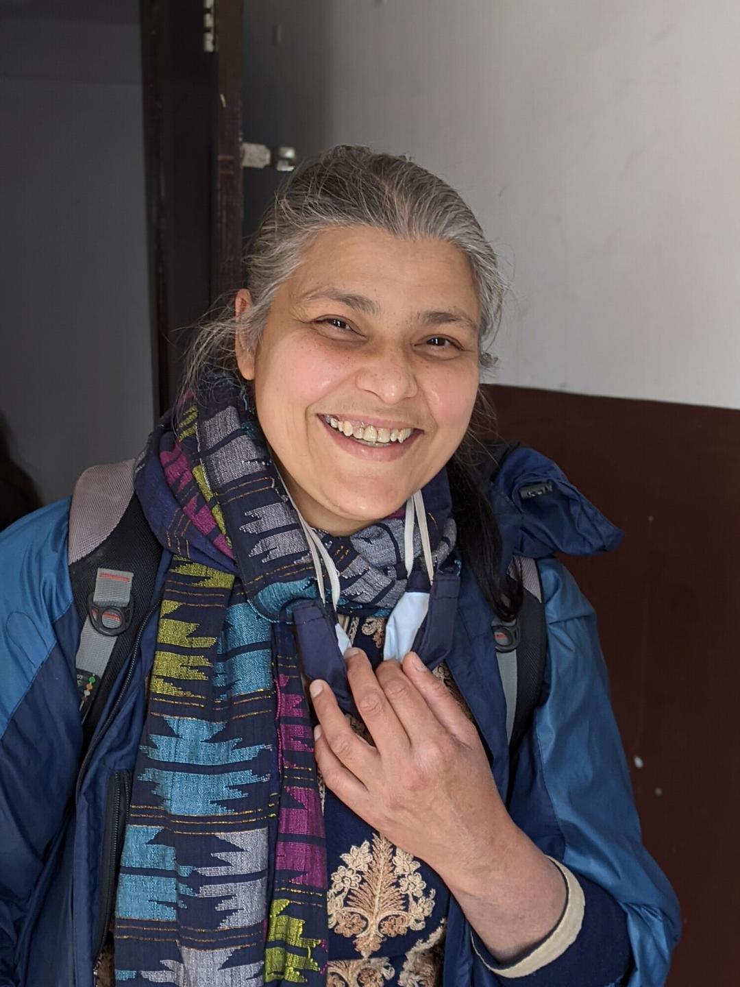 A portrait of a Nepali woman with grey hair and a colorful scarf