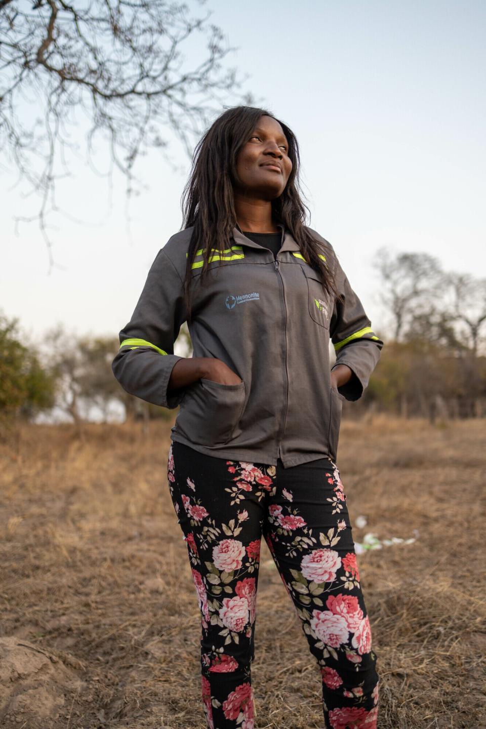 A Zimbabwe woman stands with her hands in her pockets, looking off into the distance