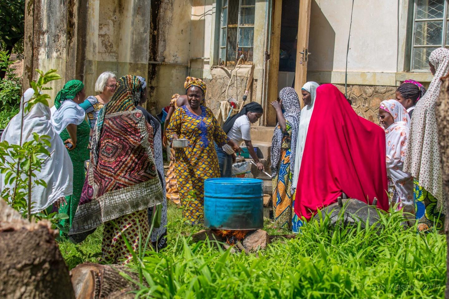 A group of women in Nigeria stand around a homemade outdoor oven