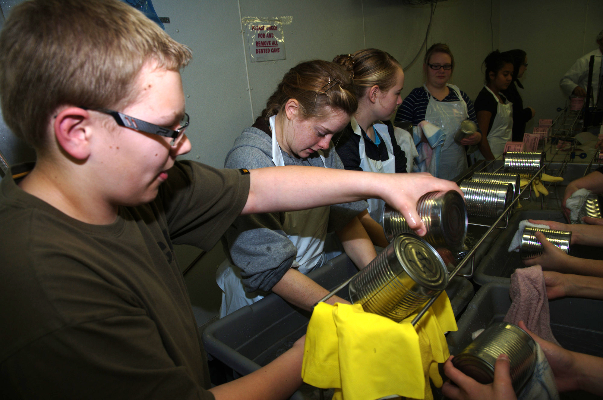 A group of young people drying off cans of meat