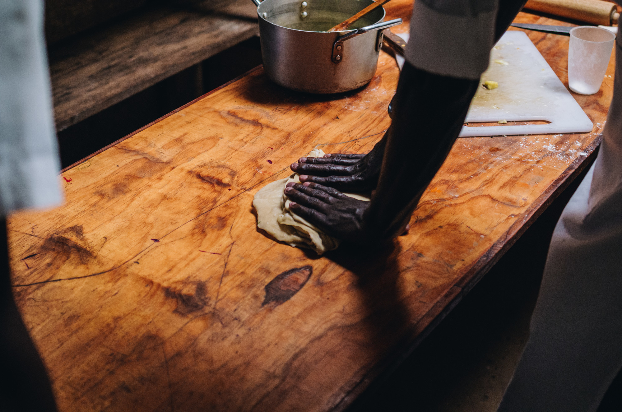 Hands kneeding dough on a wooden work surface