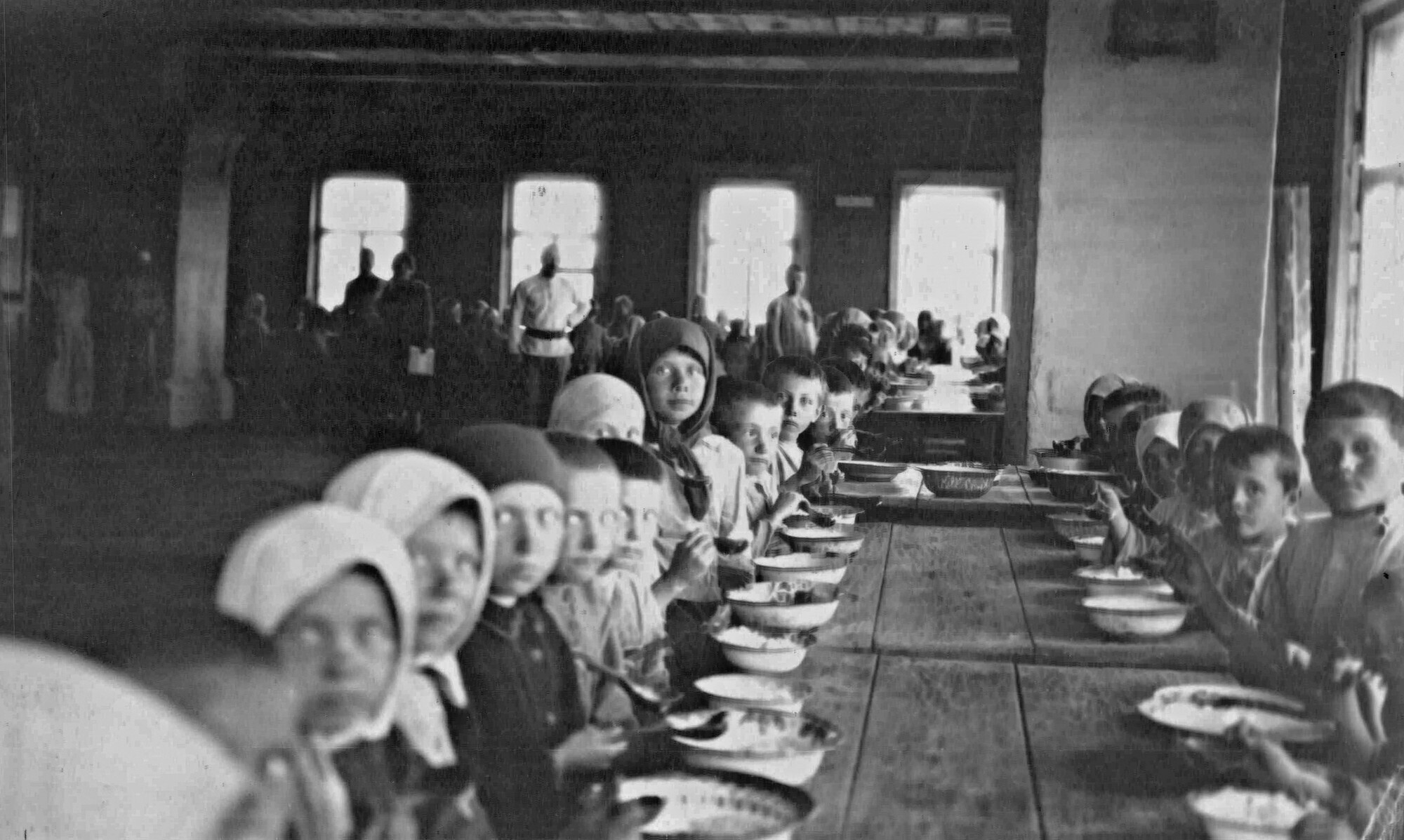 A black and white photo for the 1920s of children eating in a large dining hall