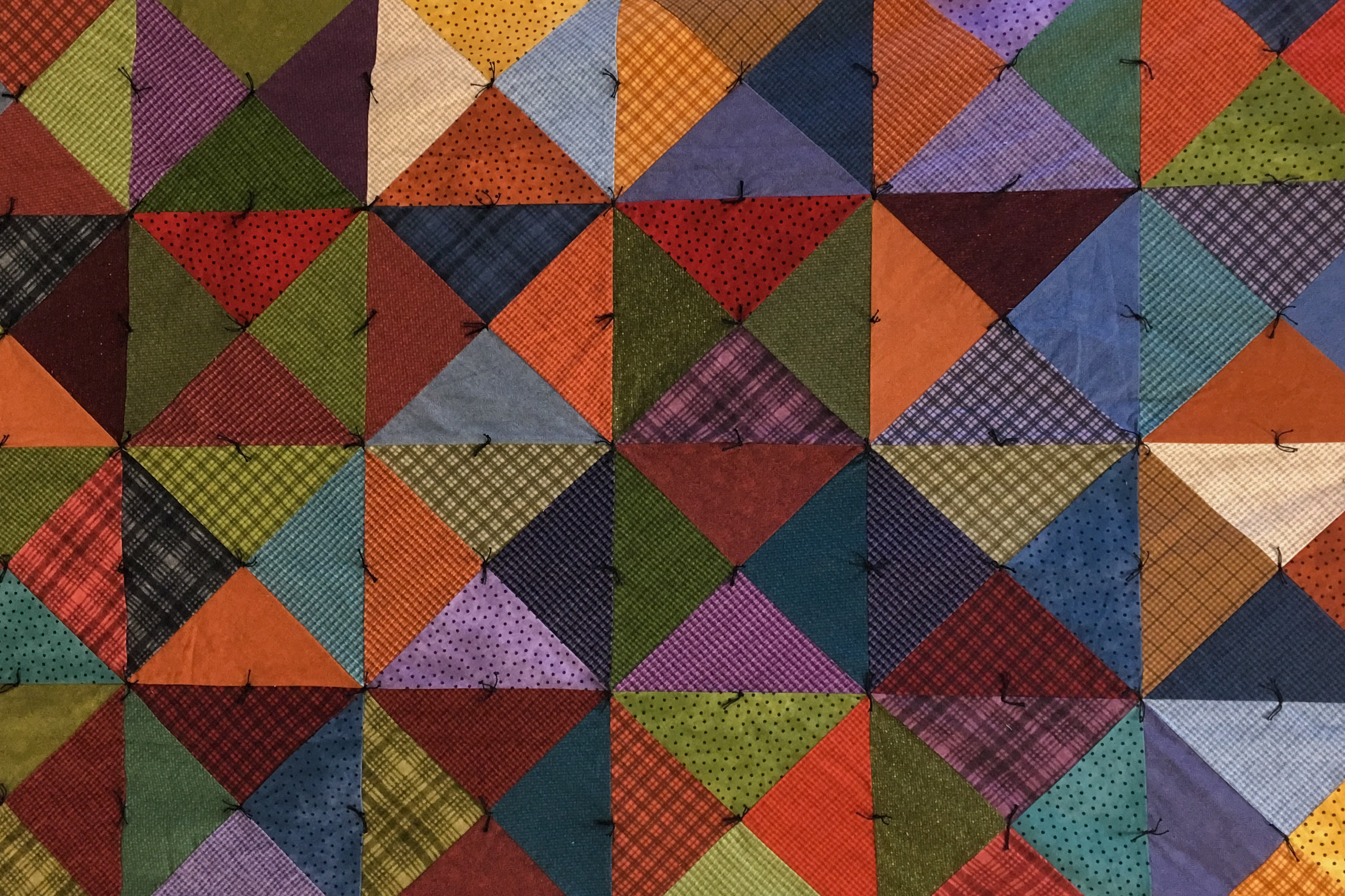A photo of a colorful quilt made with squares and triangles.