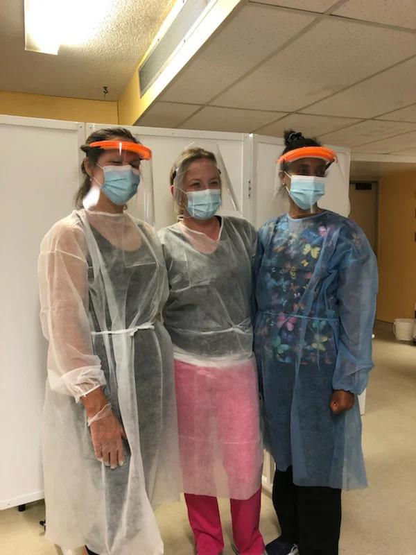 Three women standing for a photo wearing PPE