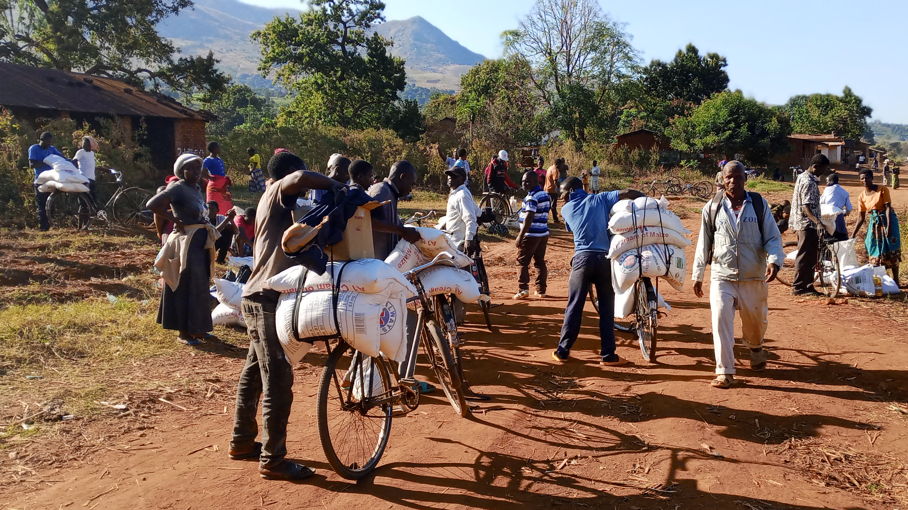 A group of people load bags and boxes onto bicycles for delivery