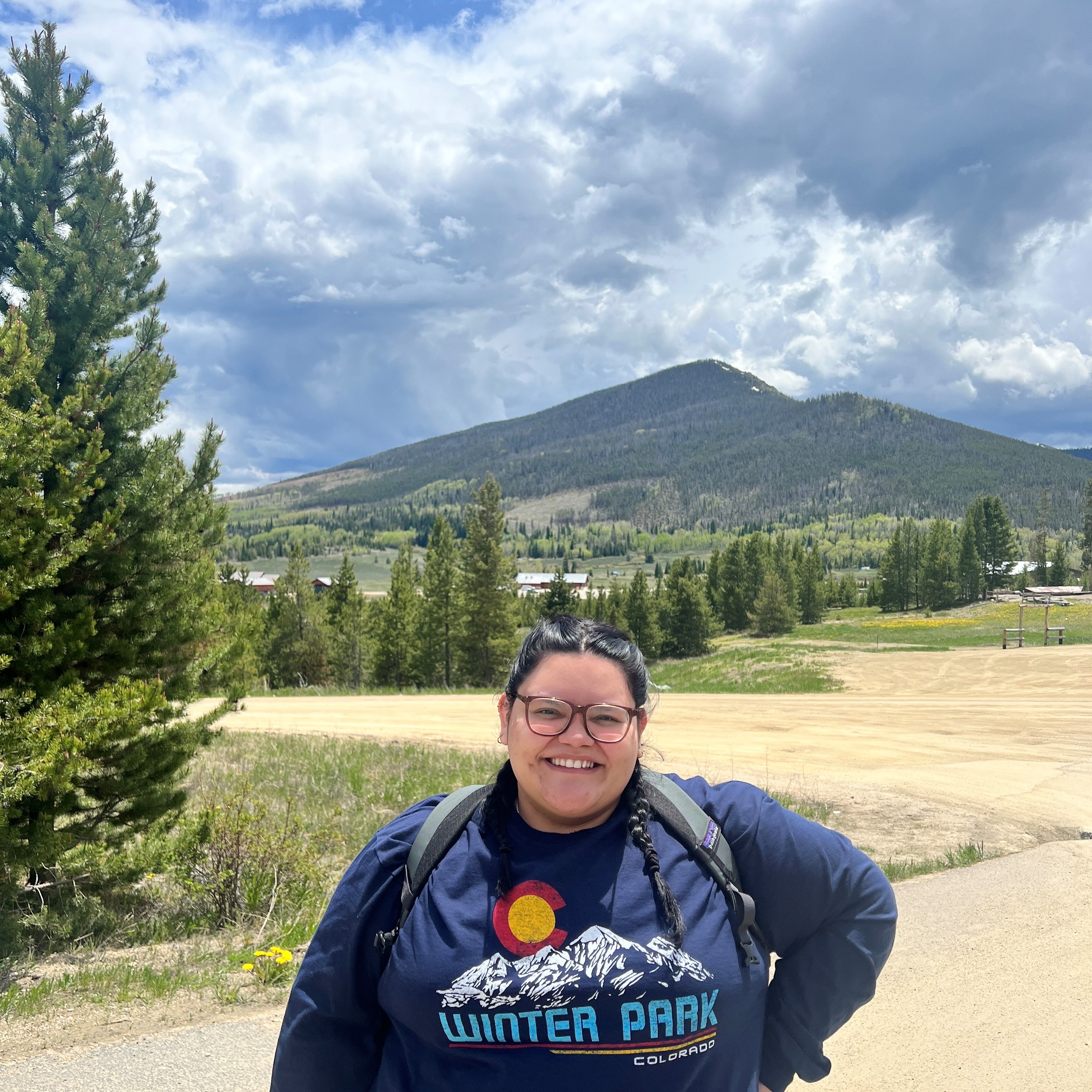 young woman stands in front of a mountain