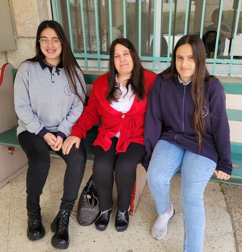 a mother and two daughters sitting on a bench