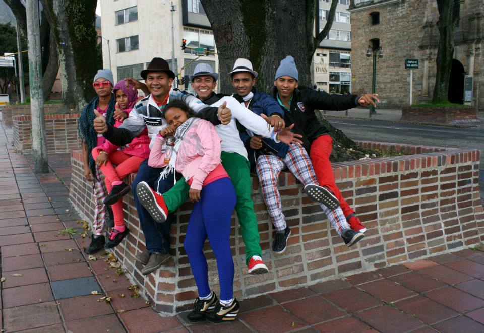 A group in colourful pants sit on a brick wall.