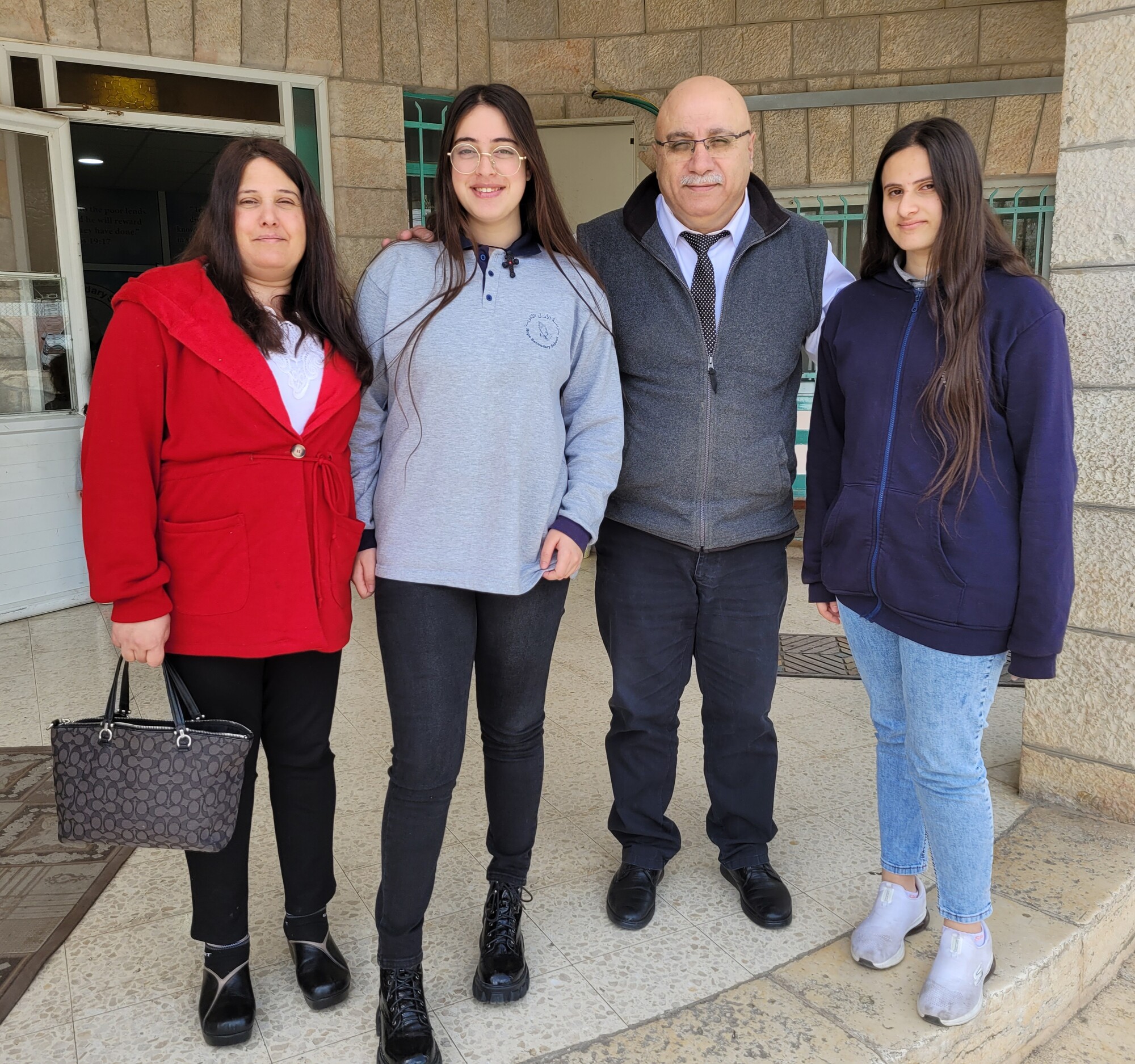 A woman and her two daughters with a school principal